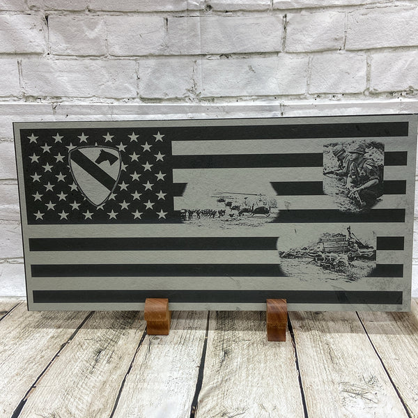 The 1st Calvary Division Patch laser engraved in the union of the US flag. Then there are three scenes from Vietnam that the 1st Cav fought in laser engraved in the stripes area of the flag. We have engraved this lovely piece on black slate and have handcrafted two wood stands that it is being displayed on.