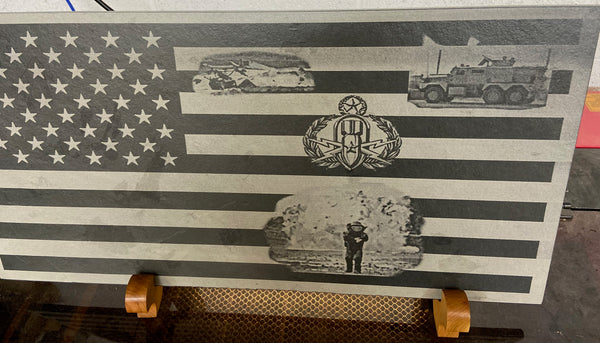 Laser engraved 24 inch x 12 inch black slate with EOD badge, bomb tech in bomb suit with bast behind, JREV, and robot on US flag.