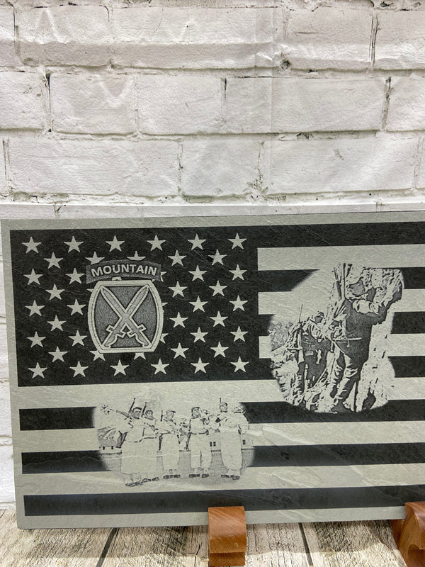 A close up of the left side of the product showing the 10th Mountain patch in the US flag union section and two scenes on the stripes. One scene is of the 10th Mountain soldiers climbing the mountains in Riva Ridge, Italy and the other is of five 10th Mountain soldiers with their ski gear getting ready to patrol in Riva Ridge area in Italy.