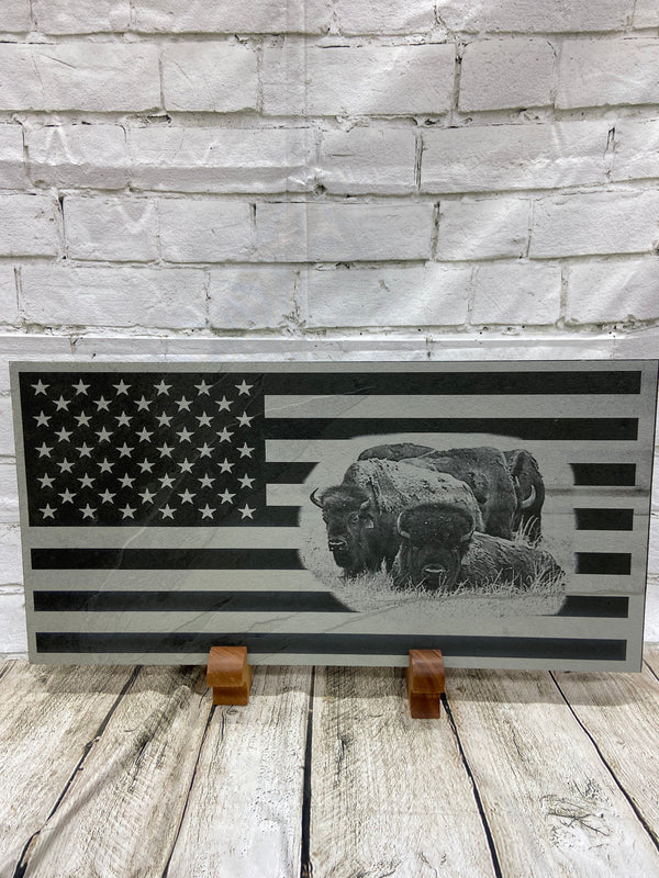 A herd of bison scene on the US flag laser engraved onto a piece of black slate.