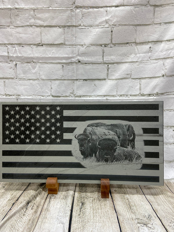 A herd of bison scene on the US flag laser engraved onto a piece of black slate.