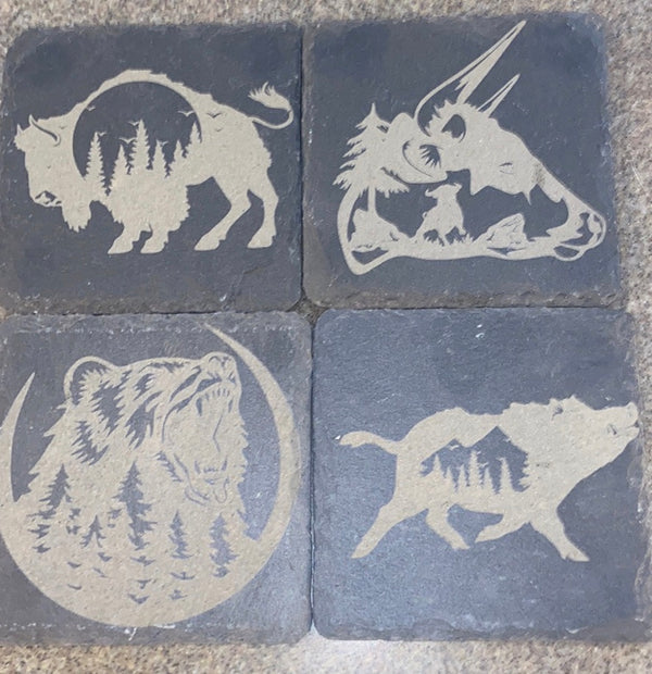 4 laser engraved black slate square coasters. With a bison, bull, bear and a boar all with a scenery in them.