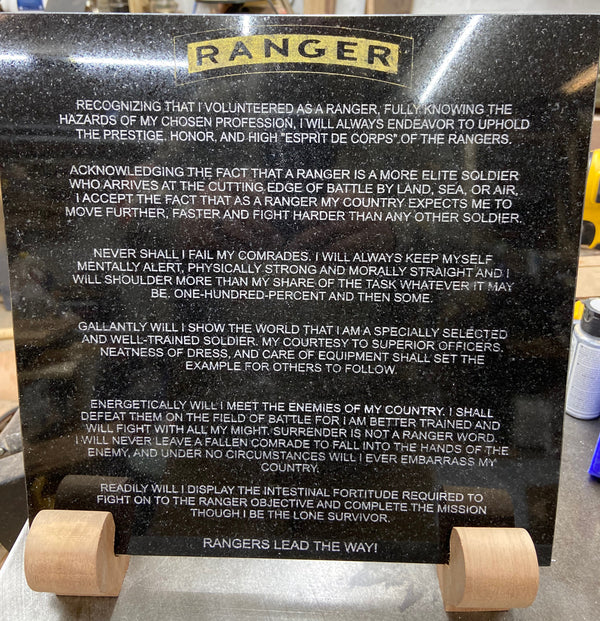 A 12 inch x 12 inch black granite laser engraved with the Ranger Creed on it. Then color filled, sitting on a mahogany stand.