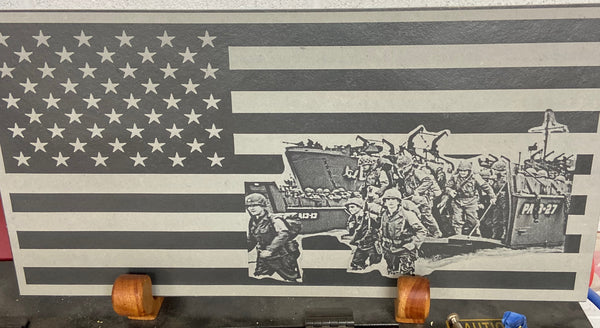 A scene from the US D-day landing on Omaha Beach World War 2, on the US flag. All of this is laser engraved onto a piece of black slate and displayed on two handcrafted wooden stands made from mahogany.