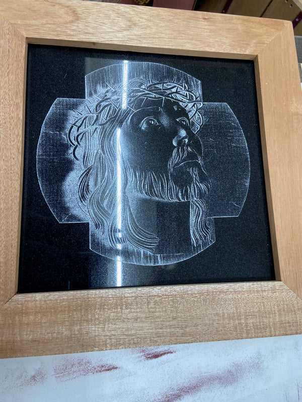 Jesus's head with cross laser engraved onto black granite. Then framed in mahogany with purple heart splines.