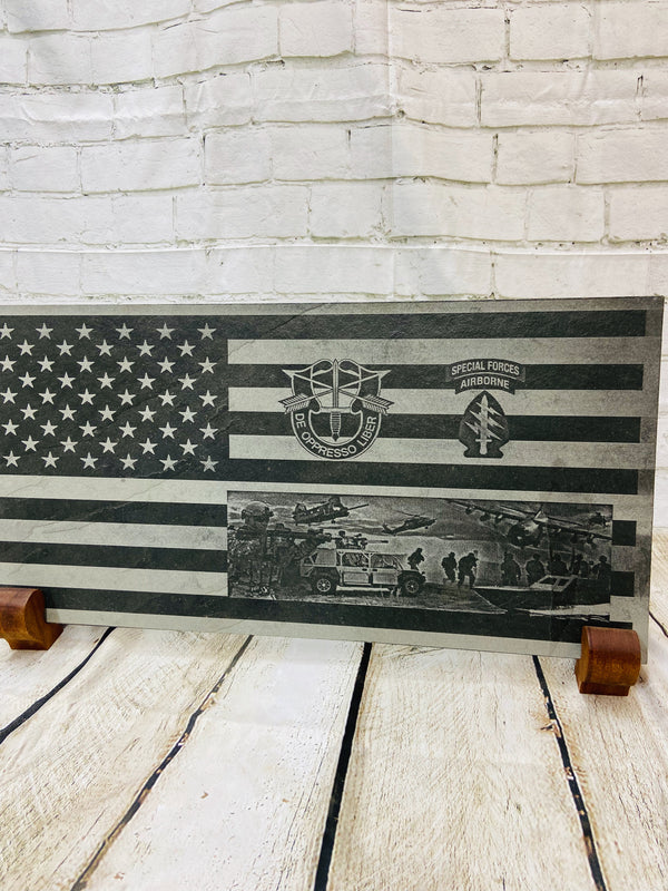 An American flag with the US Army Special Forces patch, crest and a scene with multiple SOF scenes all laser engraved on black slate.