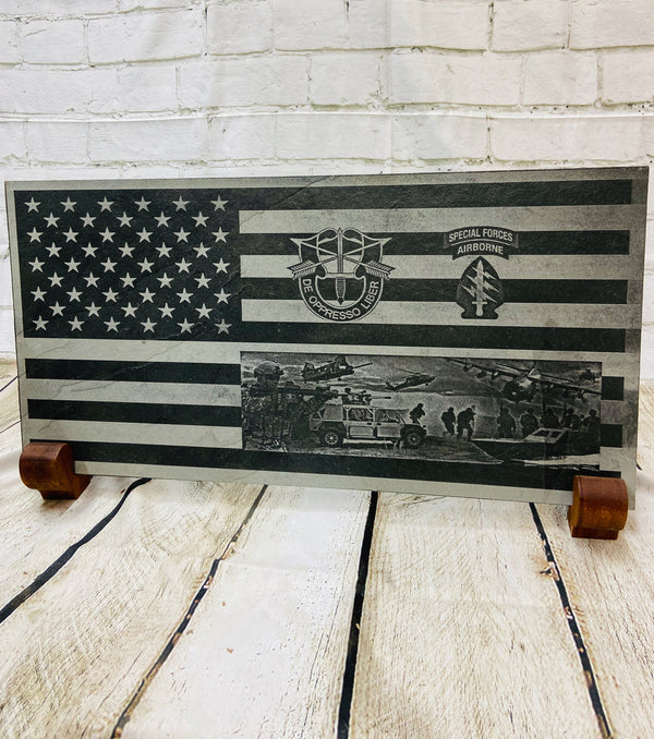 An American flag with the US Army Special Forces patch, crest and a scene with multiple SOF scenes all laser engraved on black slate.