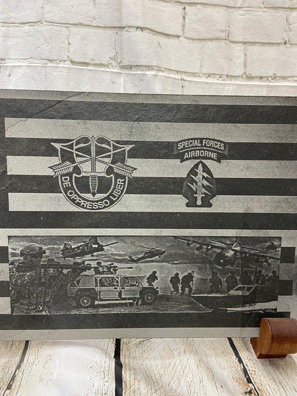 An American flag with the US Army Special Forces patch, crest and a scene with multiple SOF scenes all laser engraved on black slate.