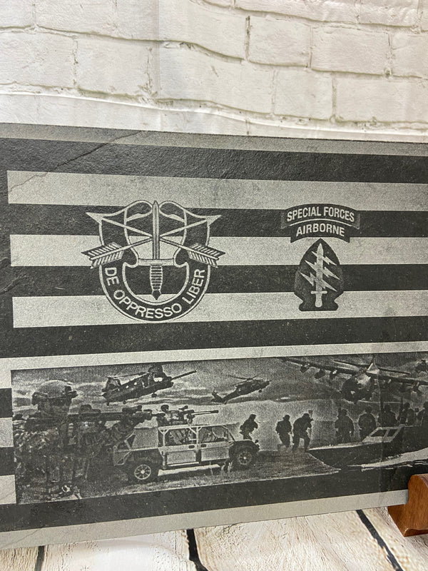 An American flag with the US Army Special Forces patch, crest and a scene with multiple SOF scenes all laser engraved on black slate.