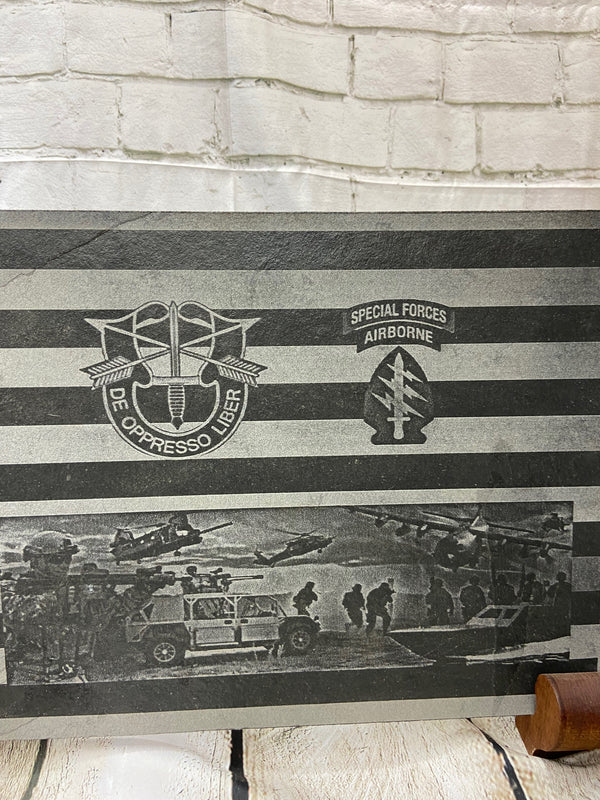 An American flag with the US Army Special Forces patch, crest and a scene with multiple SOF scenes all laser engraved on black slate.