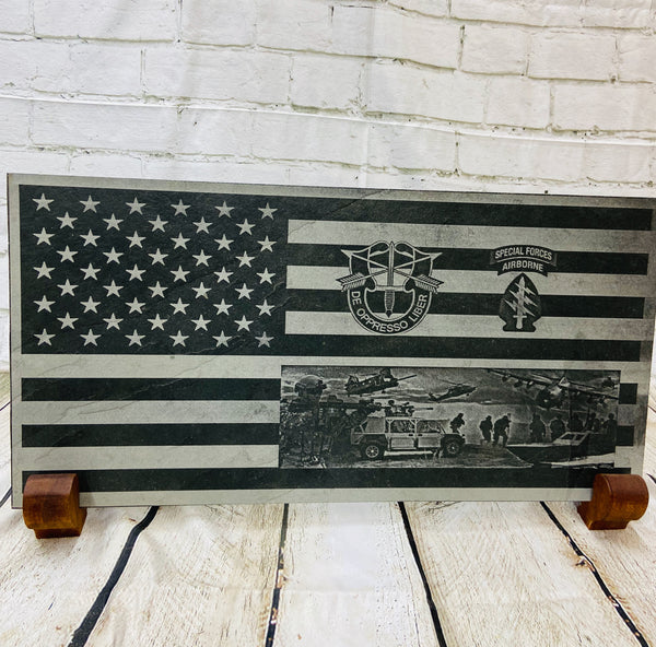 An American flag with the US Army Special Forces patch, crest and a scene with multiple SOF scenes all laser engraved on black slate.